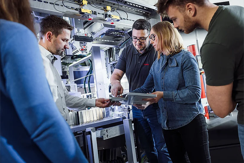 People are standing in front of a SOMIC packaging machine and receiving operator training from a SOMIC employee.